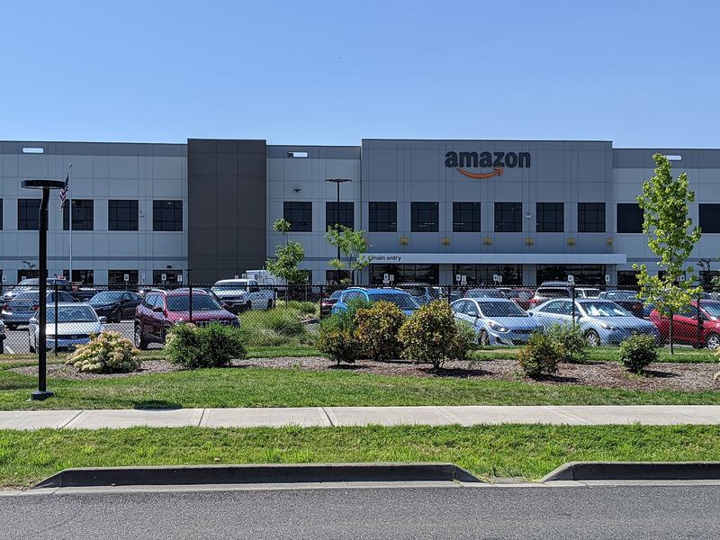 An Amazon fulfillment center building with a parking lot in front