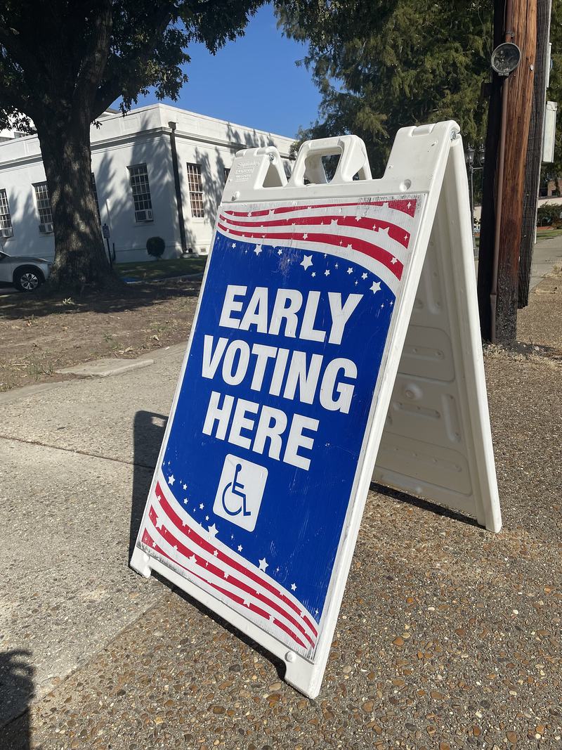 A sidewalk sign reading Early Voting Here outside a courthouse