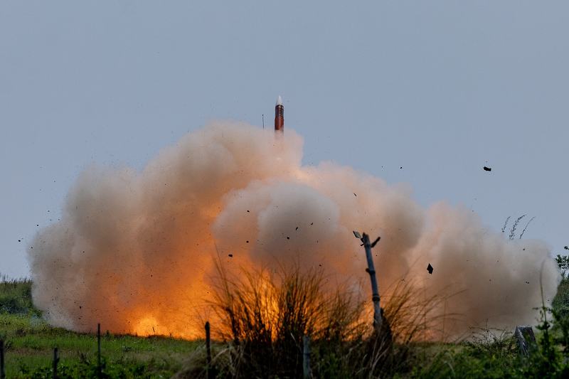 A Patriot surface-to-air missile launching from a field with a cloud of smoke